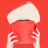 Hand placing a red Duradry deodorant stick into the cream Travel Bag